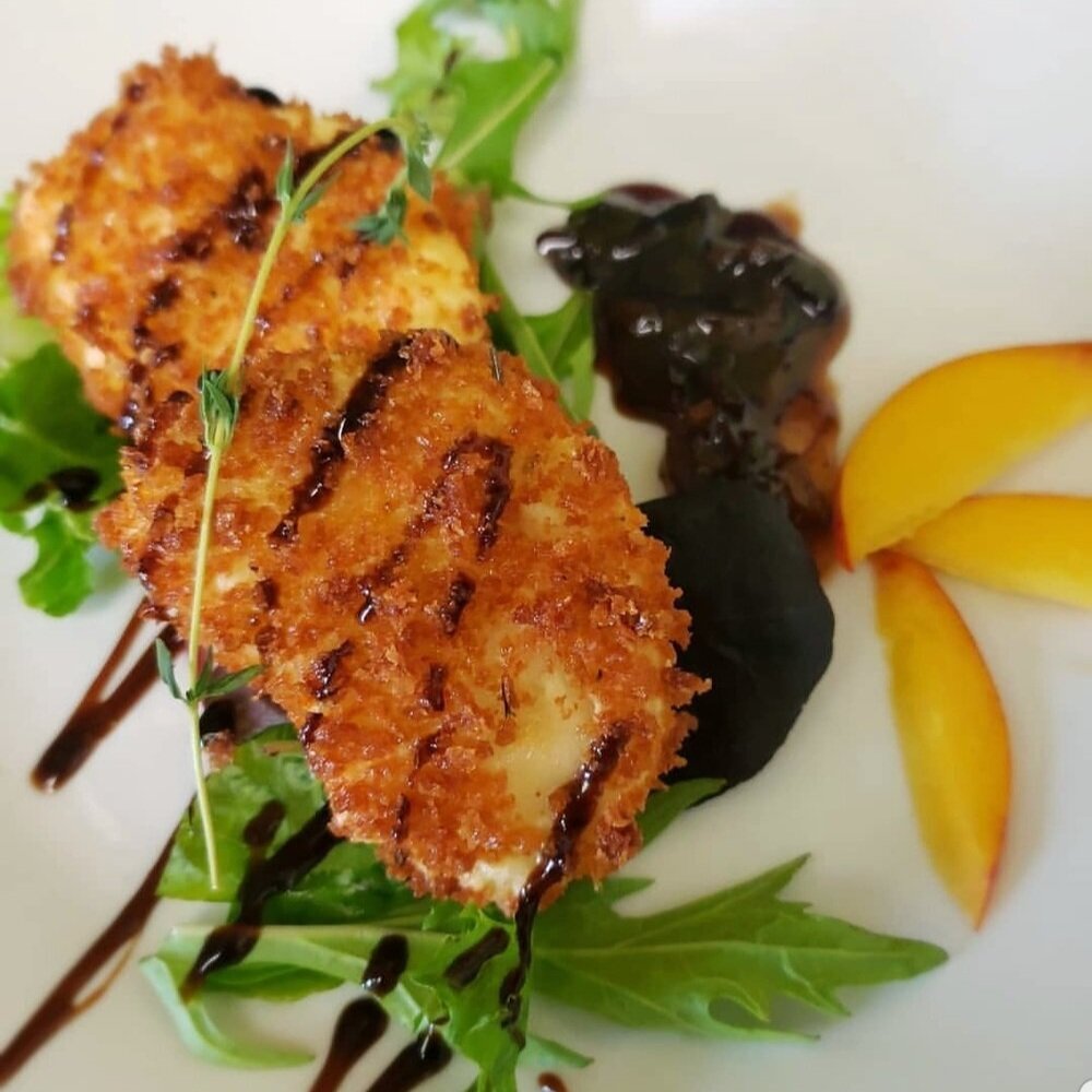 Screenshot_20190708-230638_Instagram-01 Crispy breaded fish fillet served on a bed of fresh arugula, garnished with a drizzle of balsamic reduction, accompanied by a dark sauce and slices of peach.